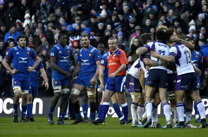 Les joueurs du XV de France (g) dépités regardent les Ecossais se congratuler après leur victoire aux Six Nations à Murrayfield, le 11 février 2018