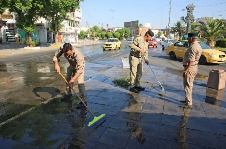 Des forces de sécurité irakiennes nettoient les rues à Bagdad après la levée du couvre-feu imposé en raison de manifestations, le 5 octobre 2019