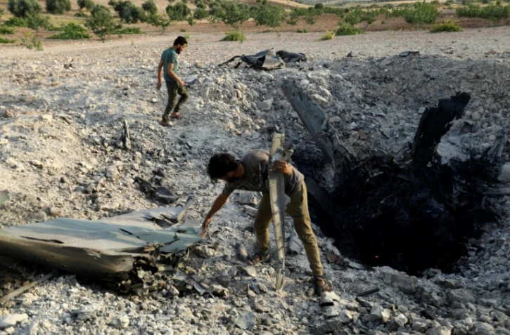 Des rebelles sériens près d'un avion du régime abattu près de Khan Cheikhoun, dans le sud de la procince d'Idleb, le 14 août 2019 en Syrie