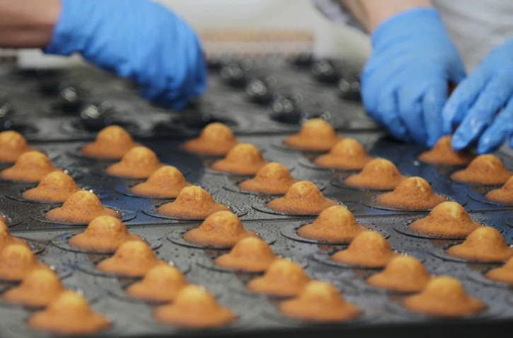 Des employĂ©s de la biscuiterie Jeannette arrangent les madeleines qui viennent d'ĂȘtre prodouites dans l'unitĂ© de production de Demouville, prĂšs de Caen, le 26 janvier 2016