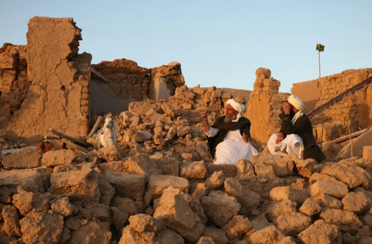 Des Afghans sont assis parmi les décombres de leurs maisons rasées dans le village de Sarbuland, dans la province d'Hérat, le octobre 2023