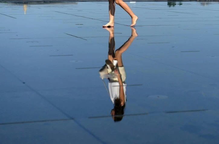 Reflet d'une femme sur le mirroir d'eau dans le centre de Bordeaux où la population vient se rafraîchir, le 19 juin 2017
