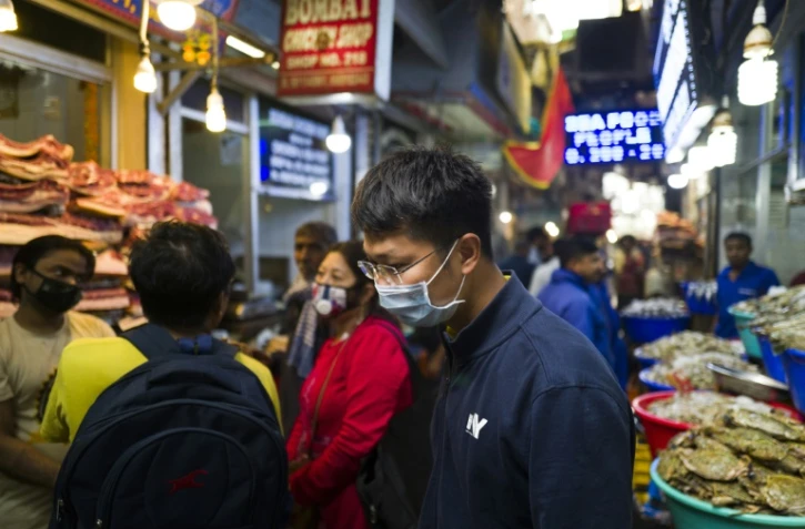 Des personnes portant un masque de protection font leurs courses dans un marché de viande et de poisson, le 14 mars 2020 à New Delhi, en Inde