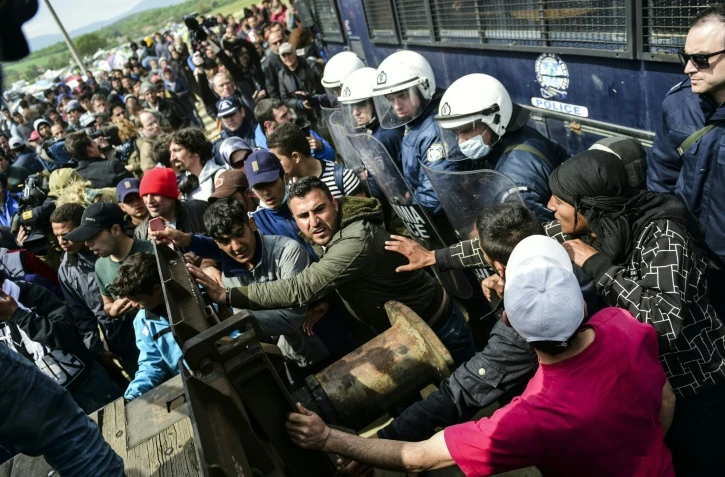 Des migrants tentent de percer une barricade installée par la police grecque à Idomeni, à la frontière avec la Macédoine, le 11 avril 2016 