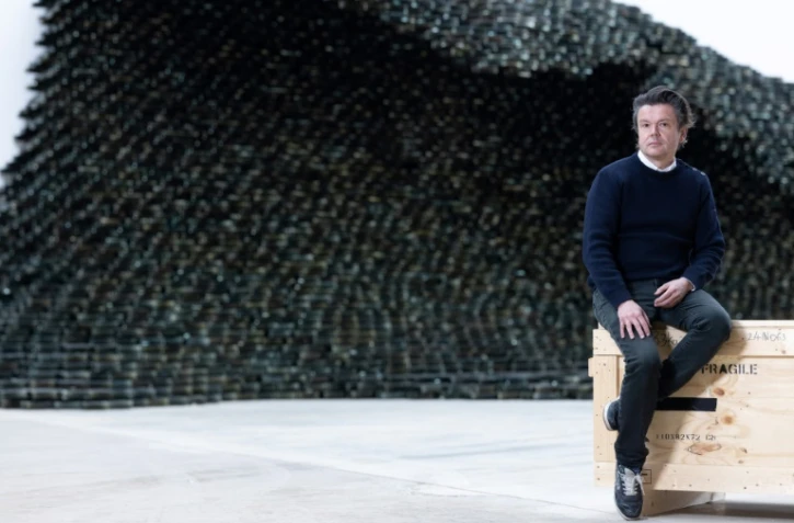 L'artiste français Jean-Michel Othoniel devant l'une de ses œuvres composées de 10 000 briques de verre noir en forme de vague, intitulée "Big Wave", dans son atelier de Montreuil, près de Paris, le 27 février 2025