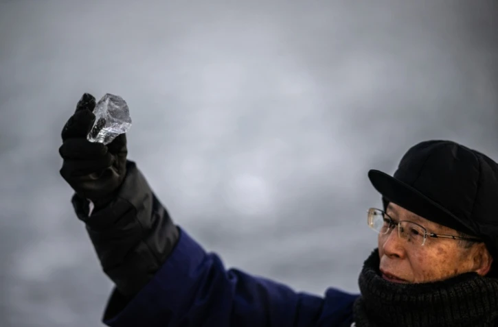 Kiyoshi Miyasaka, prêtre japonais du culte shinto, brandit un morceau de glace du lac Suwa, le 29 janvier 2026 dans la préfecture de Nagano, dans le centre de l'archipel 