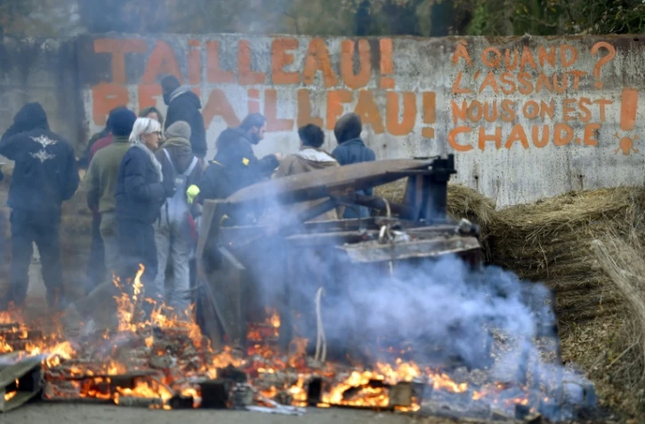 Des militants hostiles au projet d'aéroport nantais devant un slogan ciblant Bruno Retailleau, le président de la région Pays de la Loire, sur une barricade dans le territoire qu'ils occupent à Notre-Dame des Landes le 2 décembre 2016 