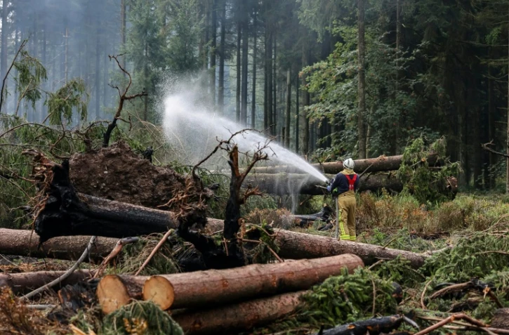 Un pompier asperge le sol d'eau le sol pour l'humidifier lors des opérations visant à contenir un incendie de forêt dans la réserve naturelle des Hautes Fagnes le 20 août 2026