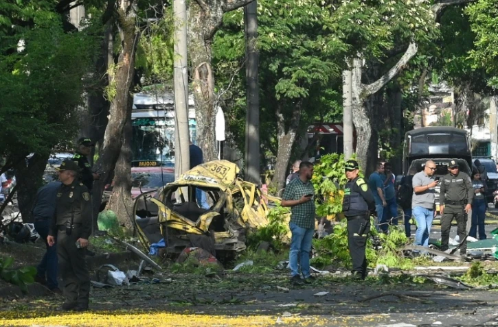 Des membres de la police colombienne inspectent la zone d'une explosion au camion piégé à Cali, en Colombie, le 21 août 2025