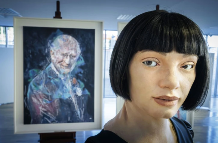 Le robot artiste gynoïde Ai-Da devant le portrait du roi Charles III qu'il a peint, exposé en marge du Sommet mondial AI for Good organisé par l'Union internationale des télécommunications (UIT) à Genève, le 9 juillet 2025