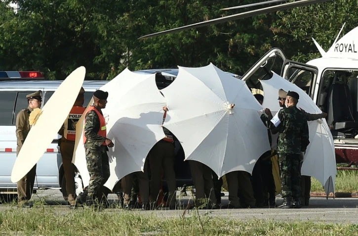 Des policiers et des militaires recouvrent une civière avec des parapluies le 9 juillet 2018 alors que se poursuivent les opérations de sauvetage pour de jeunes footballeurs coincés dans une grotte en Thaïlande 