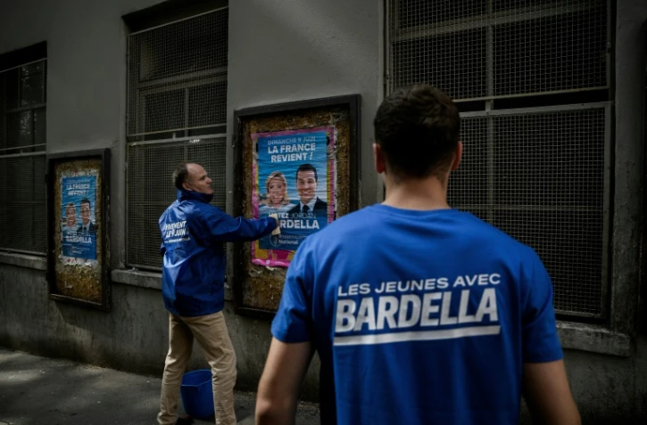 Des bĂ©nĂ©voles du RN collent des affiches de campagne de Jordan Bardella, prĂ©sident du parti et tĂȘte de liste aux europĂ©ennes, le 6 mai 2024 Ă Lyon