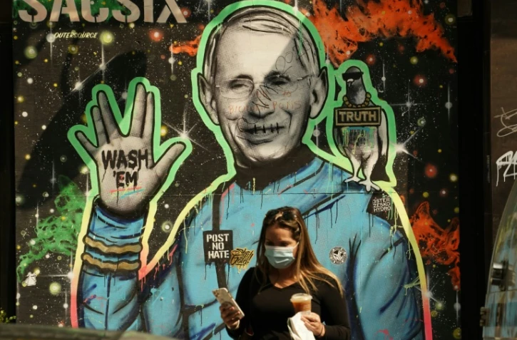 Des passants marchent devant une fresque représentant le Dr Anthony Fauci, directeur de l'Institut américain des maladies infectieuses, le 16 septembre 2020 à New York