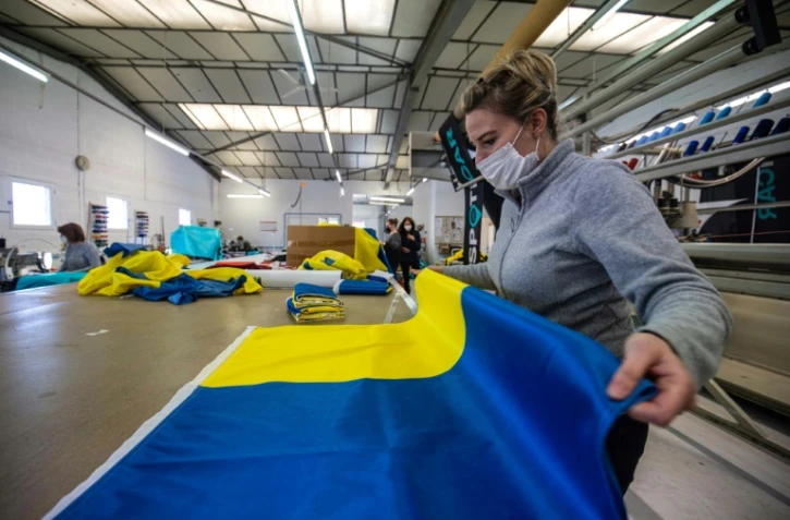 Une employée plie un drapeau aux couleurs de l'Ukraine fabriqué dans l'atelier Borney d'Argentan, dans l'Orne, le 8 mars 2022