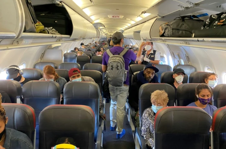 Des passagers d'un vol d'American Airlines Ă destination de Charlotte portent un masque de proection, Ă l'exception d'un seul, le 3 mai 2020 Ă New York