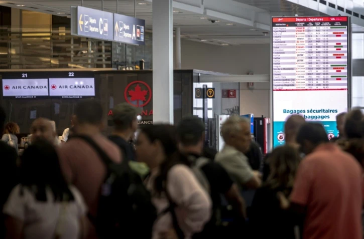 Des voyageurs consultent un panneau d'information sur les vols annulés d'Air Canada à l'aéroport Pierre-Elliott Trudeau à Montréal, au Québec, le 17 août 2025 au Canada
