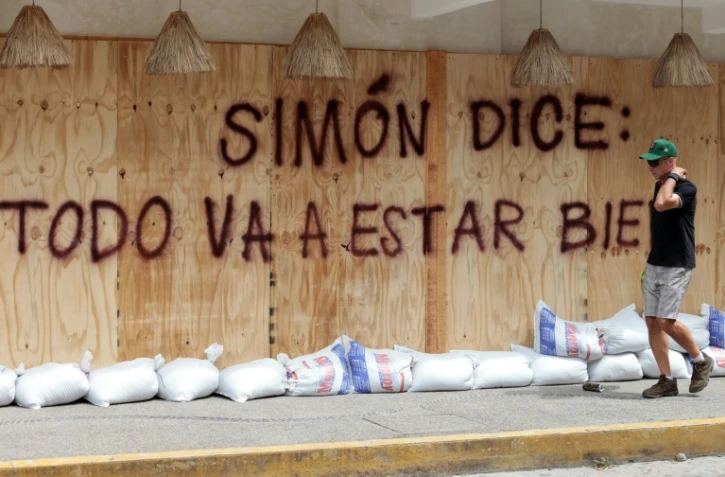 Un homme passe devant un message: "Simon a dit: +tout va bien se passer+", peint sur des planches de protection en prévision de l'arrivée du cyclone Simon à Puerto Vallarta au Mexique, le 10 octobre 2026