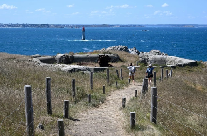 Des visiteurs regardent les ruines d'un bunker allemand avec un canon rouillé, le 5 août 2022 sur l'île de Cézembre, au large de Saint-Malo