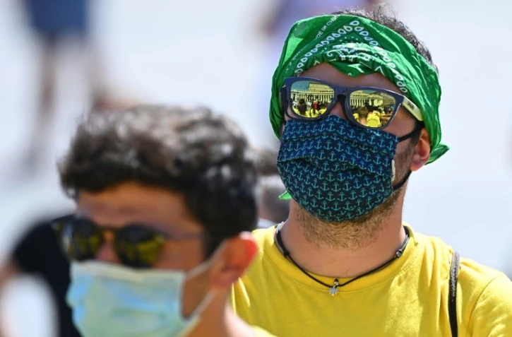 Protégés par des masques contre le coronavirus, des fidèles écoutent la prière dite par le pape sur la place Saint-Pierre au Vatican le 23 août 2020