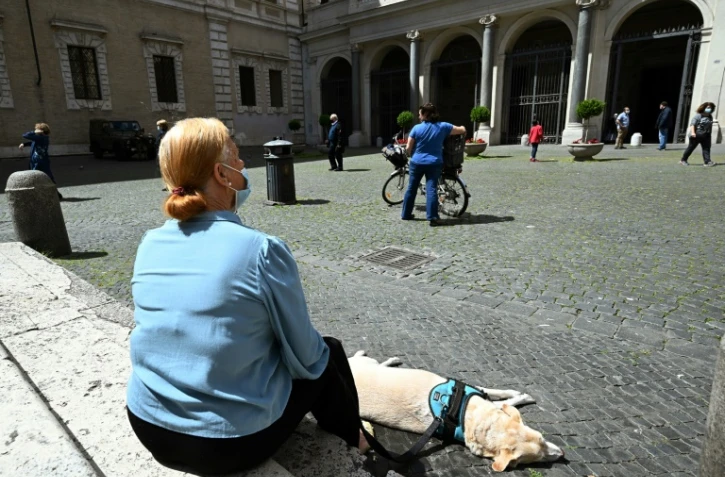 Une femme et son chien se reposent sur la place Santa Maria à Trastevere, à Rome, le 3 mai 2020.