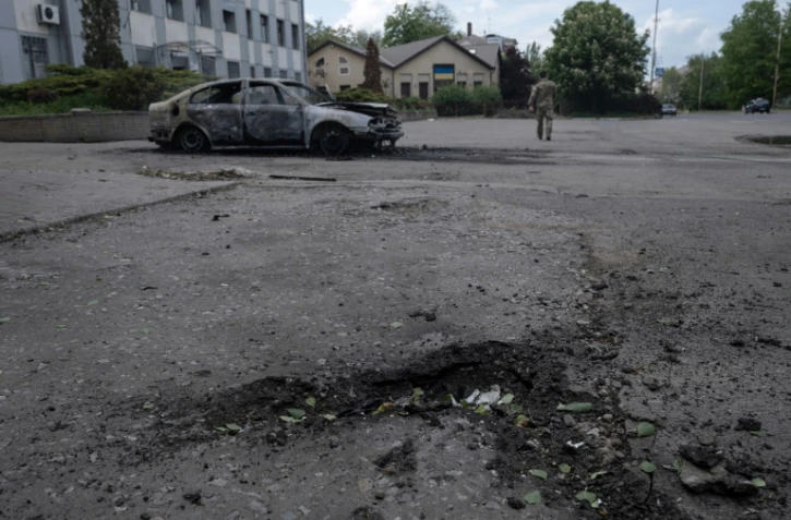 Photo prise le 16 mai 2025 et publiée le 17 mai 2025 par le service de presse de la 93e brigade mécanisée séparée de Kholodnyi Yar des forces terrestres ukrainiennes montrant un cratère à côté d'une voiture calcinée et le corps d'une victime à l'intérieur après une attaque de drone à Kostyantynivka, dans la région de Donetsk
