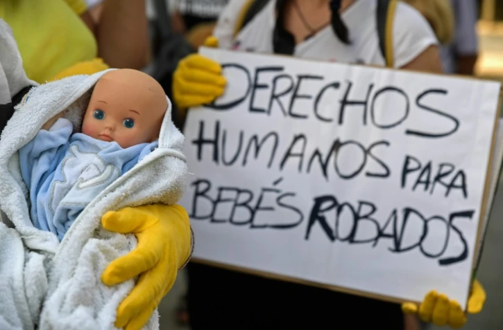 Des manifestants arborent un poupon et une pancarte réclamant des "droits" pour "les bébés volés" sous la dictature de Franco, à Madrid le 26 juin 2018