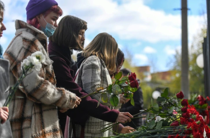 Des étudiants déposent des oeillets au mémorial du campus de Perm le 21 septembre 2021, au lendemain de la tuerie