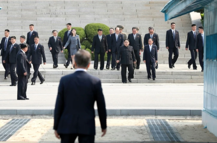 Le leader nord-coréen Kim Jong-Un (c) se dirige vers la ligne de démarcation à la rencontre du président sud-coréen Moon Jae-in (de dos) avant le début du sommet intercoréen, le 27 avril 2018 à Panmunjom