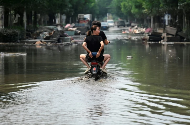 Des habitants de Zhuozhou en scooter dans l'eau, après de fortes pluies qui ont provoqué des inondations dans la province du Hebei, le 9 août 2023
