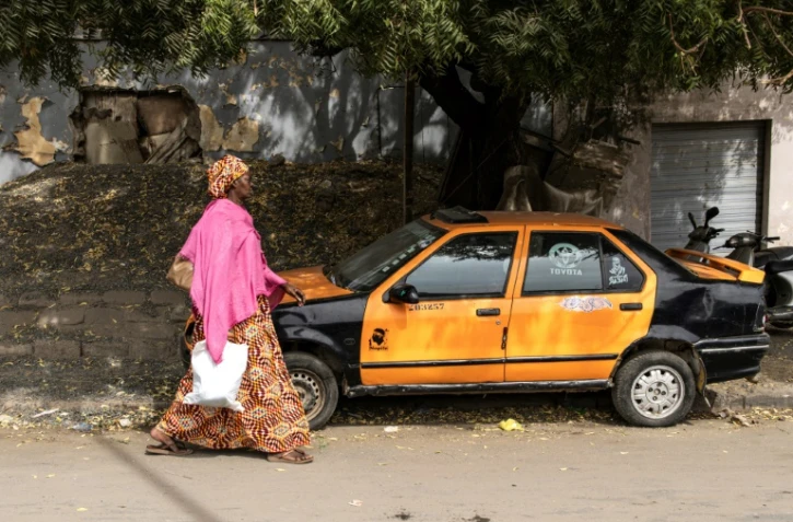 Une femme passe devant un taxi à Dakar, le 13 février 2024