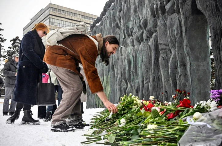 Des gens déposent des fleurs en hommage à l'opposant russe Alexeï Navalny devant le momument en mémoire des victimes de la répression politique, le 17 février 2024 à Moscou