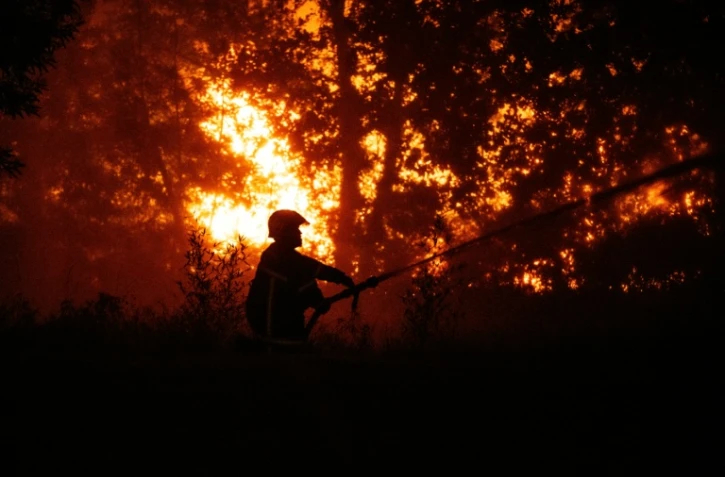 Un sapeur-pompier arrose la forêt près d'une zone résidentielle menacée par l'incendie proche de Lège-Cap-Ferret en Gironde, le 23 juillet 2026