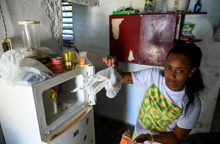 Diana Ruiz montre la nourriture qu'elle a dans son réfrigérateur, chez elle à La Havane, le 27 mars 2024 à Cuba