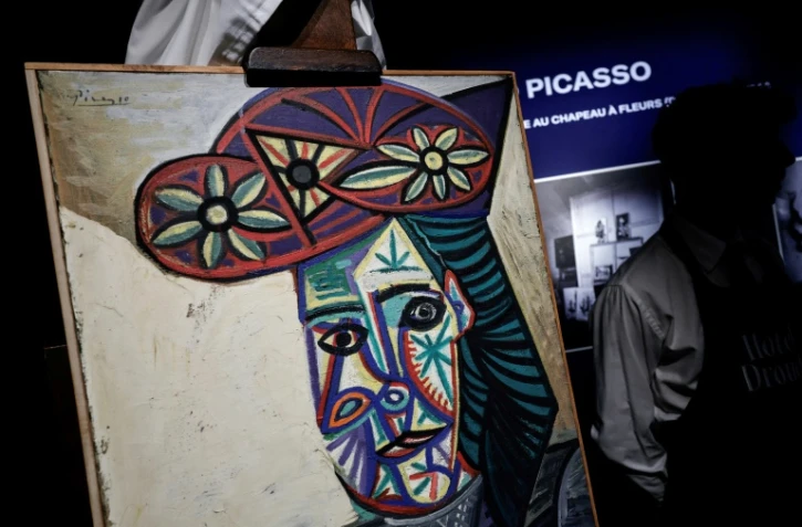 Un employé de l'Hôtel Drouot dévoile le tableau de Pablo Picasso "Buste de femme au chapeau à fleurs" représentant Dora Maar, le 18 septembre 2025 à l'Hôtel Drouot à Paris, avant la mise aux enchères de l'oeuvre le 24 octobre 2025