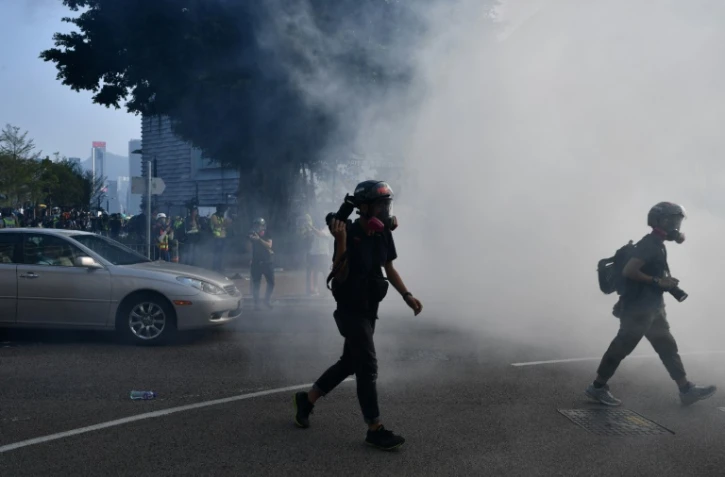 Des photographes fuient les gaz lacrymogènes tirés par la police, à Hong Kong le 27 octobre 2019