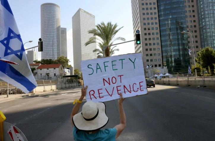 Une Israélienne brandit une pancarte réclamant "Sécurité, pas de vengeance", le 16 octobre 2023, pendant un sit-in permanent à Tel Aviv devant le ministère de la Défense depuis le massacre perpétré en Israël le 7 octobre par le Hamas qui a fait 1.400 morts, surtout des civils israéliens
