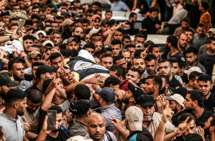 Des Palestiniens portent le corps de deux victimes des frappes israéliennes à Gaza, le 5 août 2022