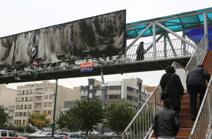 Image prise à Téhéran le 19 novembre 2019, montrant un grand panneau publicitaire au-dessus d'une autoroute urbaine incendié.  