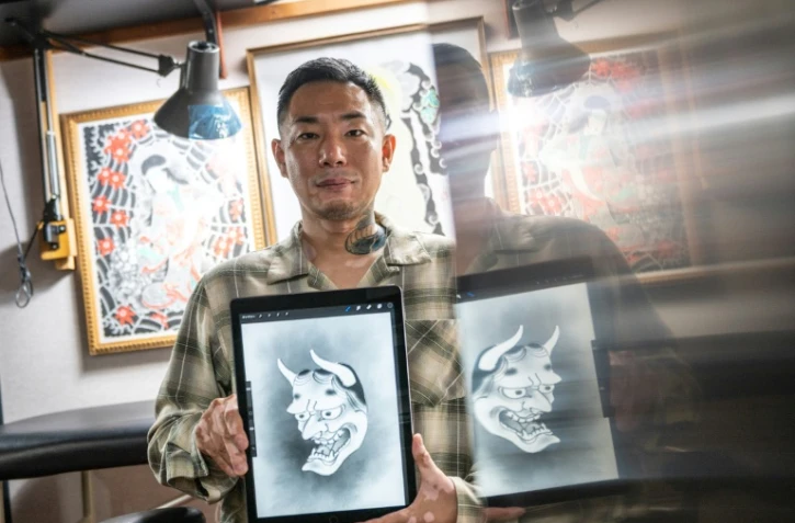 Le tatoueur japonais Ichi Hatano montre un dessin de "hannya" (fantôme femme)  sur tablette tactile dans son studio à Tokyo, le 22 juin 2021