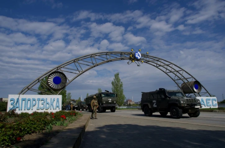 Des véhicules militaires russes passent l'entrée de la centrale nucléaire de Zaporijjia, le 1er mai 2022 à Energodar