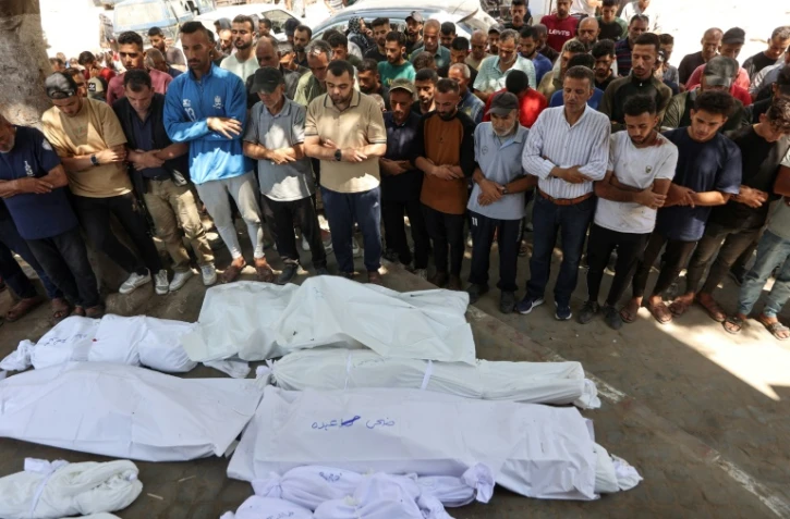 Des Palestiniens se recueillent devant des corps enveloppés dans des draps blancs, le 3 juillet 2025 dans la ville de Gaza