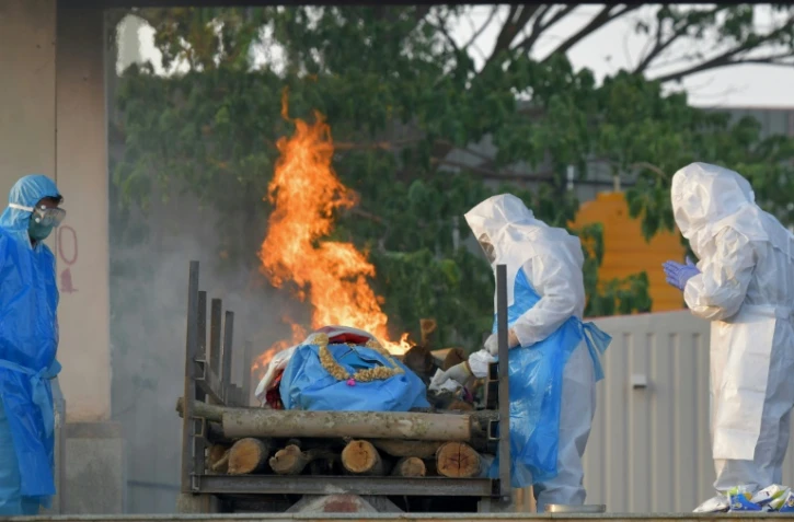 Des proches d'une personne décédée du Covid-19 appliquent un rite funéraire dans un crématorium de Bangalore, en Inde, le 26 avril 2021