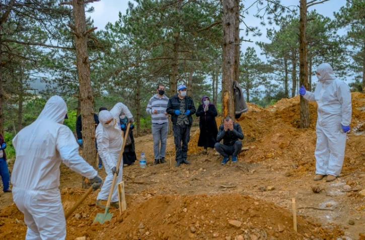 Des personnels funéraires en combinaison de protection enterrent une personne décédée du coronavirus en présence de la famille, le 21 mai 2020 à Istanbul, en Turquie