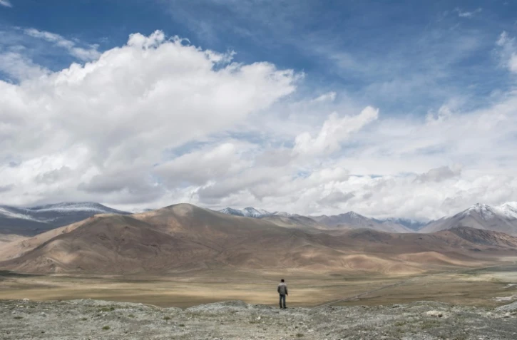 Photo archive montrant un homme regardant une portion de la route de l'amitié entre la Chine et le Pakistan (à droite) et la montagne Karakorum près de Tashkurgan dans la province chnoise du Xinjiang, le 28 juin 2017