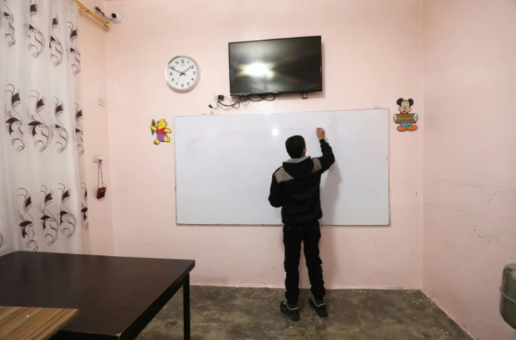 Un adolescent écrit sur un tableau au centre "Hori" pour anciens enfants jihadistes géré par les forces kurdes à Tal Maarouf, dans le nord-est de la Syrie, le 11 février 2018