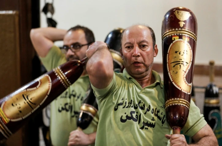Des Iraniens s'entraînent avec des sortes de massues pour la pratique d'un sport traditionnel, dans le gymnase "zourkhaneh" (maison de force) à Téhéran le 27 février 2018