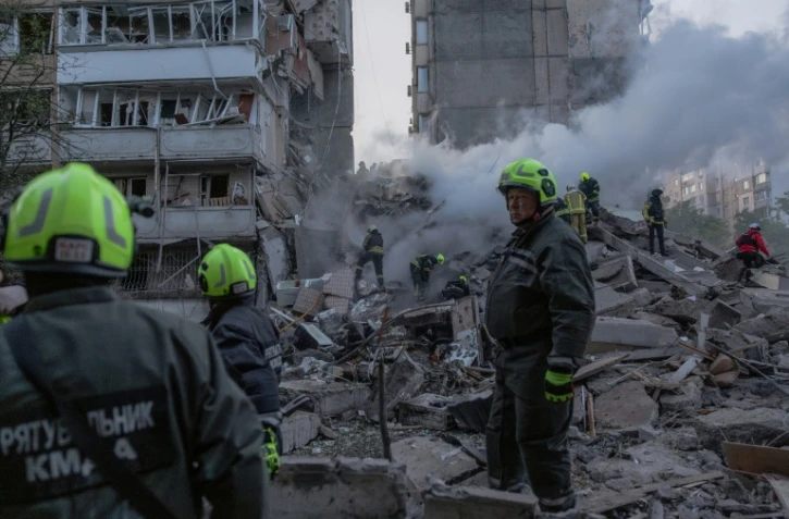 Les secouristes dans les ruines d'un immeuble détruit par une frappe russe à Kiev, le 14 mai 2026