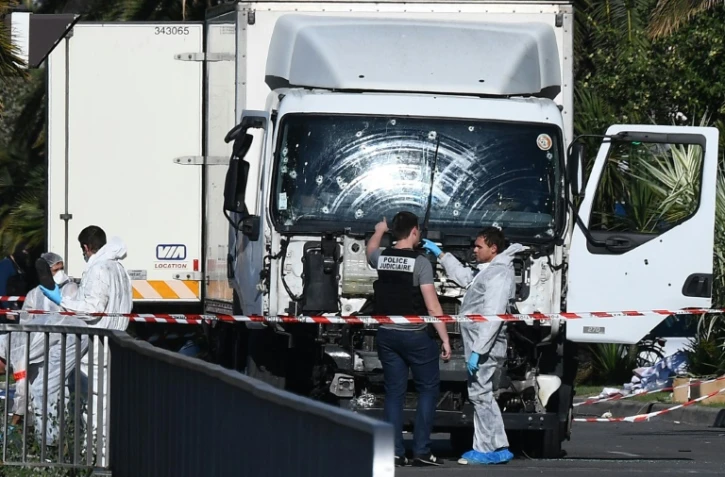 Des experts scientifiques de la police devant le camion criblé de balles de l'auteur de l'attentat sanglant de Nice, le 15 juillet 2016