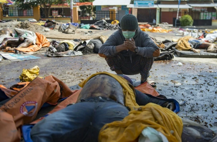 Un survivant du tsunami devant le corps de sa femme retrouvé parmi des dépouilles, le 2 octobre 2018 à Palu, ville indonésienne frappée par un séisme et un tsunami
