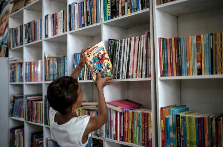 Un jeune garçon replace un livre sur une étagère de la bibliothèque "Mundo da Lua" à Rio de Janeiro, le 10 mars 2020